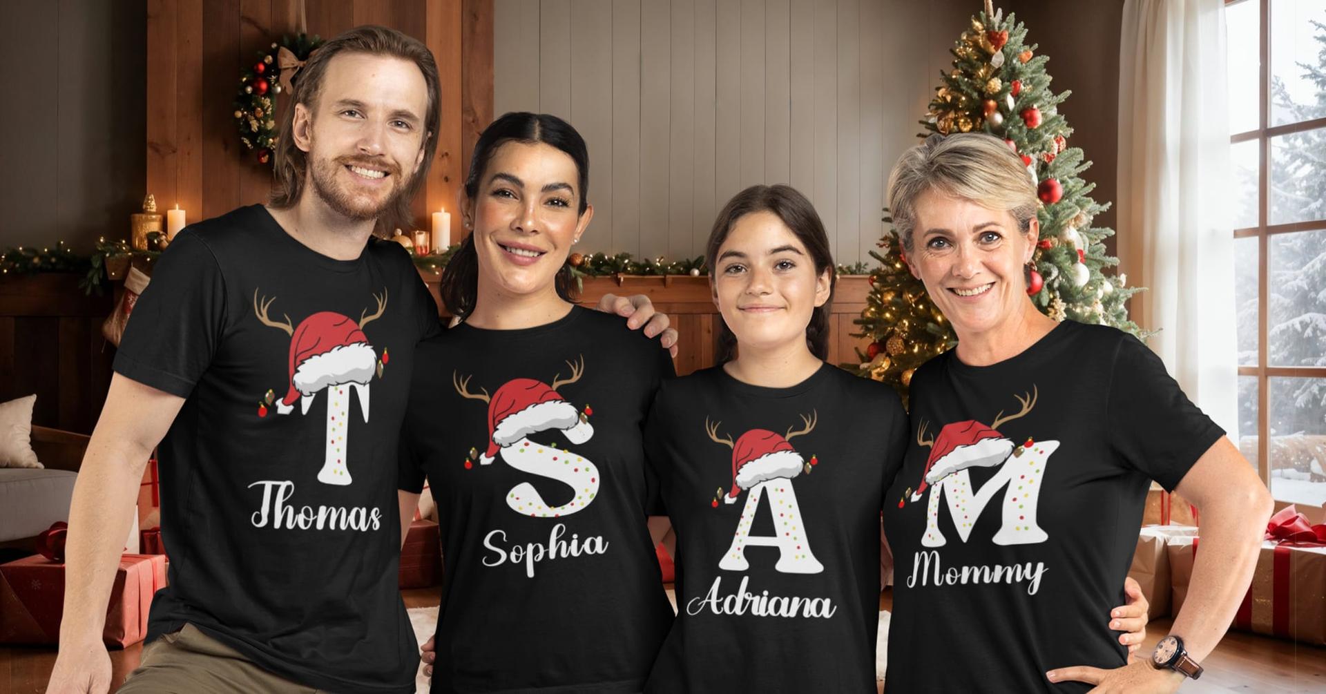 A family of four in matching initial Christmas shirts by the tree