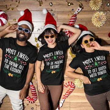Three friends in Santa hats and black Most Likely To Christmas shirts, posing on a festive wooden floor