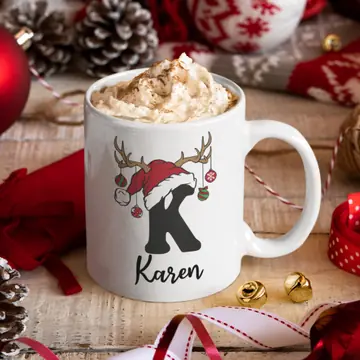 A white mug printed with a Santa-hat K and the name Karen, filled with cocoa among Christmas decorations
